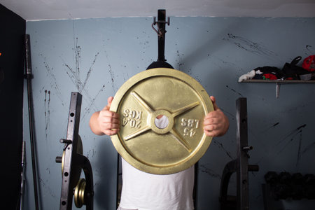 man exercising lifting iron disc weight plate in home gym. fitness concept