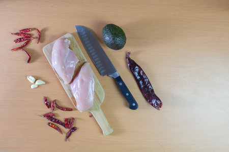 chicken breasts on wooden board with chef's knife, Mexican chilies and avocado. mexican food