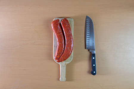 Raw pork sausage on wooden board and chef's knife.の写真素材