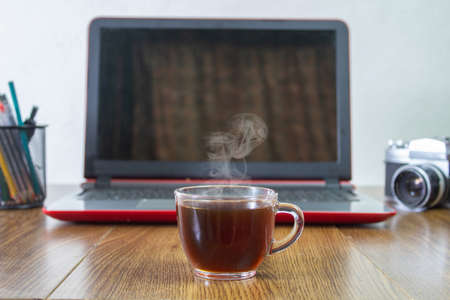 cup of hot coffee in front of laptop in home office conceptの写真素材