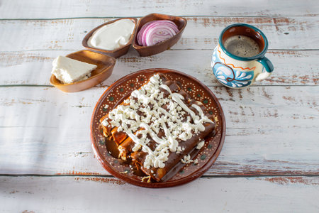 Enchiladas or mole wraps with a Mexican cup of coffee, purple onion, cream and fresh cheese. Mexican...