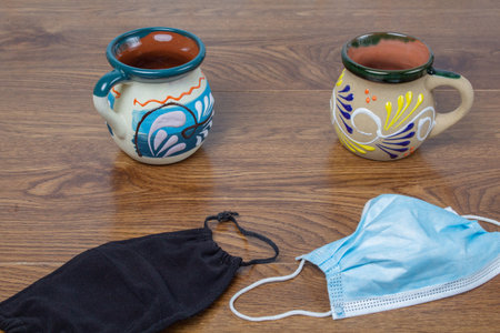 Mexican cups of coffee on tables next to face masks of different materialの写真素材