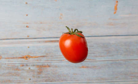 fresh organic tomato floating in front of vintage boardsの写真素材