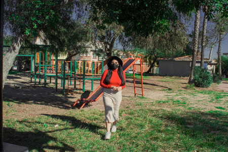 beautiful Mexican woman walking in the park in spring wearing facial mask. latin teen