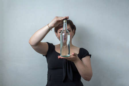 beautiful mexican woman showing bottle of white tequila, vodka or mezcalの写真素材