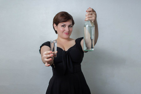 beautiful woman showing bottle and shot of white tequila, vodka or mezcalの写真素材