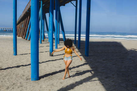 beautiful and sexy mexican woman walking under the pier on the beach in summerの写真素材