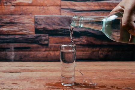 bartender serving tequila from bottle to shot glass making splash