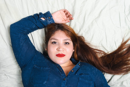 beautiful redhead plus size model lying in bed smiling. young fat modelの写真素材