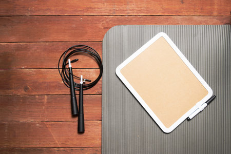 Empty blackboard on yoga mat with jump rope. workout concept