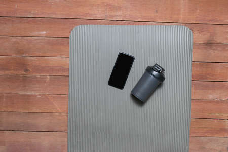 cell phone and sports shaker on yoga mat in gym studioの写真素材