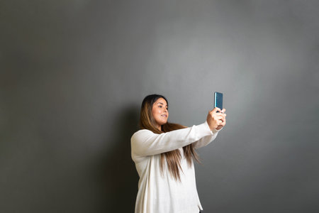 beautiful chubby young hispanic woman taking a selfie with cellphone