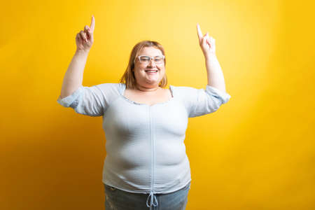 overweight young caucasian model pointing upの写真素材