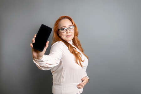 beautiful caucasian mature woman showing mobile phone screenの写真素材