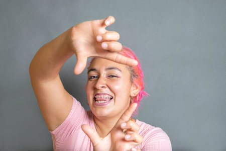 portrait of beautiful young mexican woman smiling framing her face with handsの写真素材