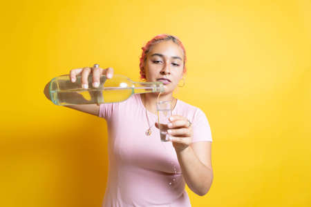 Modern Mexican young woman serving shot of tequila, mezcal or vodka bottleの写真素材