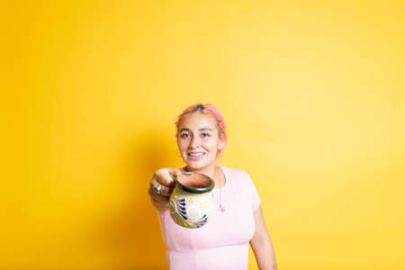 young mexican woman offering and showing colorful cup of mexican coffeeの写真素材
