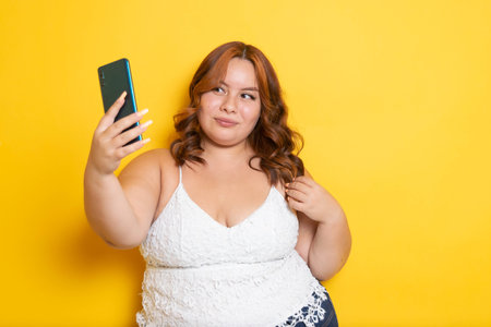 beautiful plus size young women using phone to make video call and take selfiesの写真素材