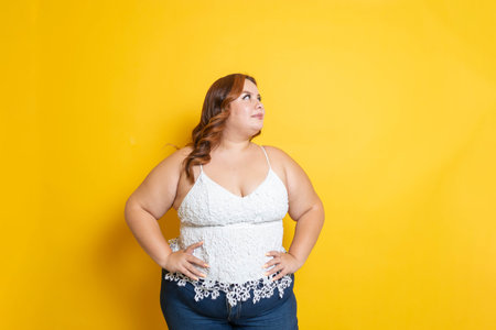 sexy overweight mexican young woman in yellow isolated background looking asideの写真素材