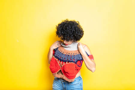 Latin young woman trying on sweater on isolated backgroundの写真素材