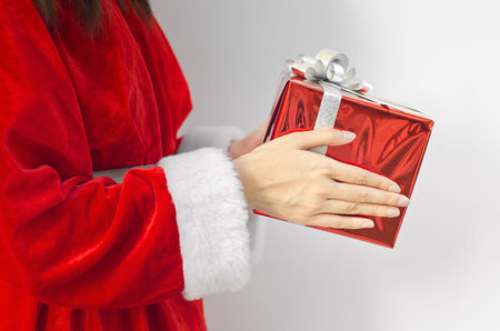Portrait of young beautiful woman in santa claus hat with red christmas gift box with grey ribbons.の写真素材