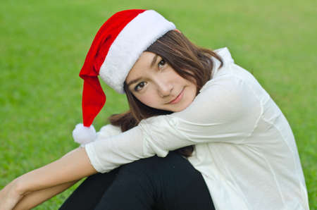 Beautiful young santa clause woman in christmas clothes smiling on the groundの写真素材