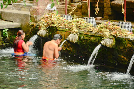 BALI, INDONESIA - OCT 17: Balinese Hindu families come to the sacred springs of Tirta Empul in Bali, Indonesia to pray and cleanse their soul on October 17, 2013.のeditorial素材