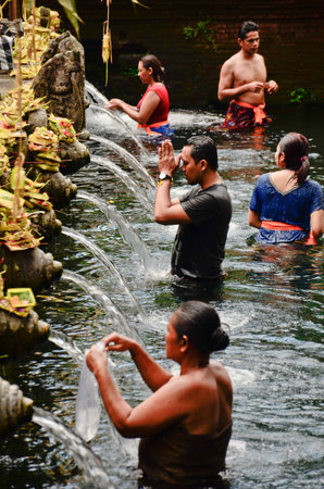 BALI, INDONESIA - OCT 17: Balinese Hindu families come to the sacred springs of Tirta Empul in Bali, Indonesia to pray and cleanse their soul on October 17, 2013.のeditorial素材