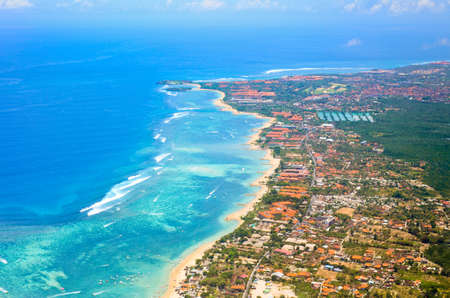 Sandy coast, buildings and blue sea with waves. Bali island view from planeの写真素材