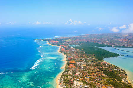 Sandy coast, buildings and blue sea with waves. Bali island view from planeの写真素材
