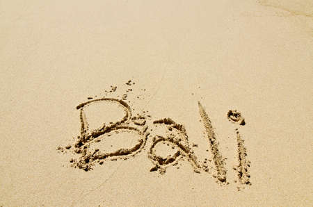Bali title with sun and palm drawing on the sand beach near the oceanの写真素材
