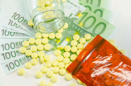 Symbolic picture for high cost of medicine with pills on moneyの写真素材