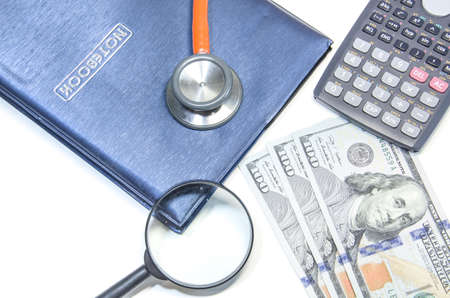 notebook ,stethoscope with us dollars and magnifying glassの写真素材