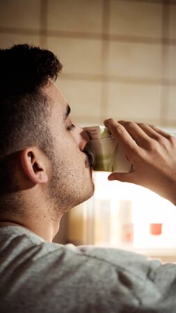 Boy drinking milk from the fridge, with the fridge open and a little bit on his back.の写真素材