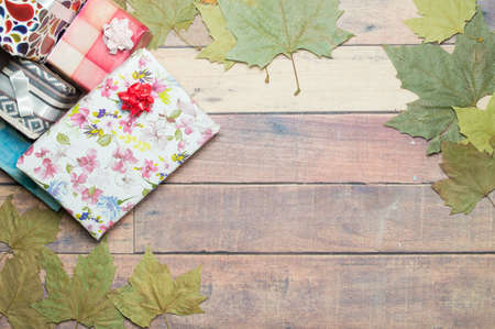 gifts and autumn leaves on wooden table to write a dedicationの写真素材