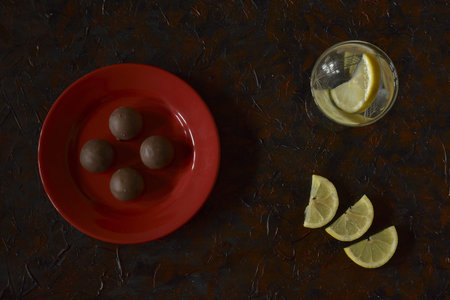 chocolates on the plate and drink with lemon slices served on the table
