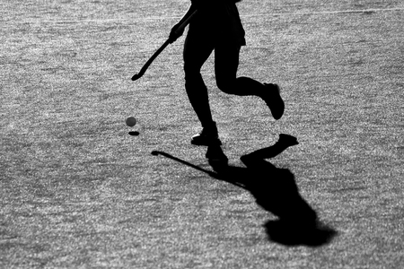 Silhouette. The shadow of a hockey players is running with a hockey stick on a hockey field.の写真素材