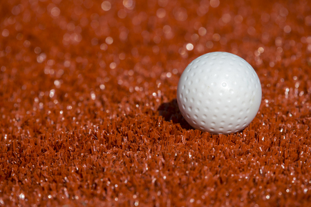 White ball for playing field hockey on the red grass backgroundの写真素材