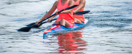 Two young woman athletes on rowing kayak on lake during competition