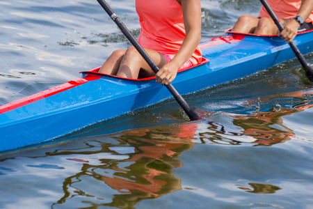 Two young woman athletes on rowing kayak on lake during competitionの写真素材