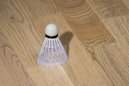 Badminton shuttlecock isolated on sports hall parquet backgroundの写真素材