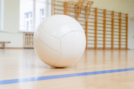 White volleyball on the ground in the school gymの写真素材