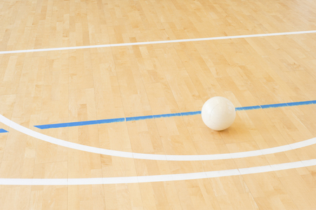 White volleyball on the ground in the school gymの写真素材