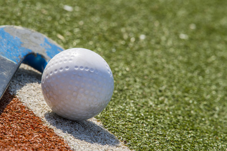 Field hockey stick and ball on brown and green grassの写真素材