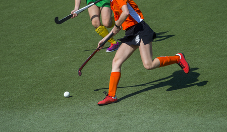 Two women battle for control of ball during field hockey gameの写真素材