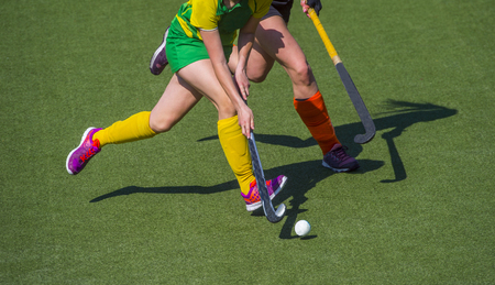 Two women battle for control of ball during field hockey gameの写真素材