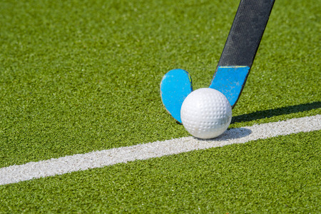 Field hockey stick and ball on green grassの写真素材