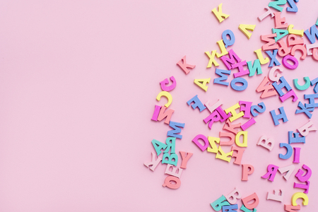 Many multicolored wooden letters on a pink background. toy letters. english alphabet. View from above. Flat lay. Copy space for textの写真素材