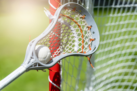 Abstract view of a lacrosse stick scooping up a ball. Sunny dayの写真素材