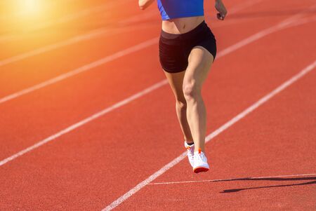 Young sporty woman running on sunny dayの写真素材